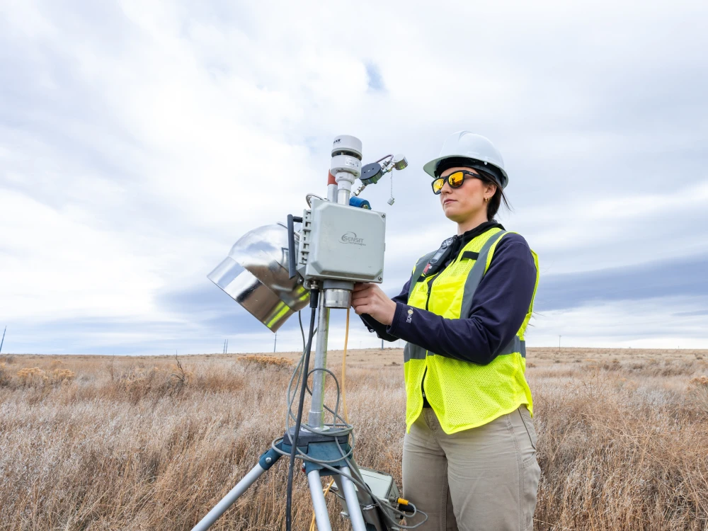 An Onterris employee setting up air sampling equipment in a field