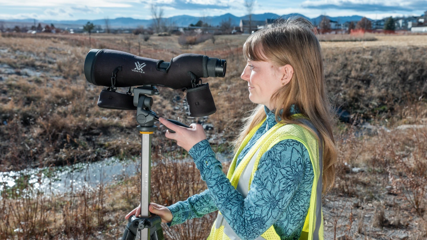 Environmental field technician using monitoring equipment outdoors.