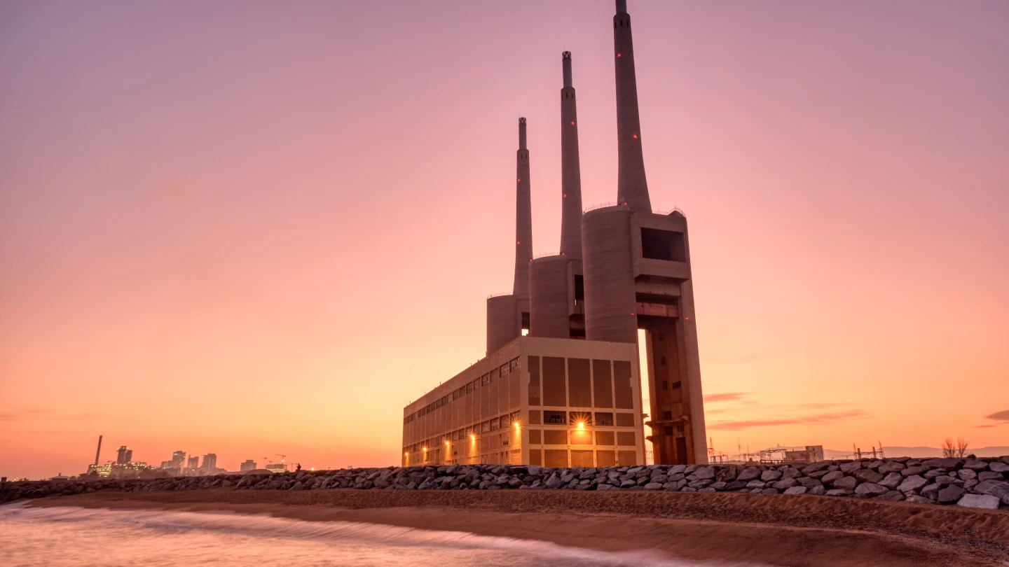 Thermal power plant with smokestacks at sunset near a waterfront