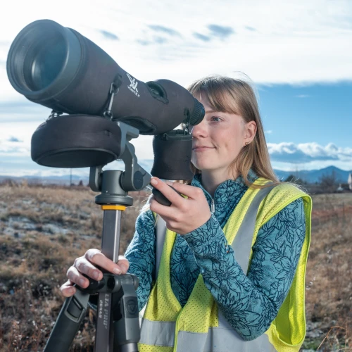 Employee using a spotting scope outdoors.