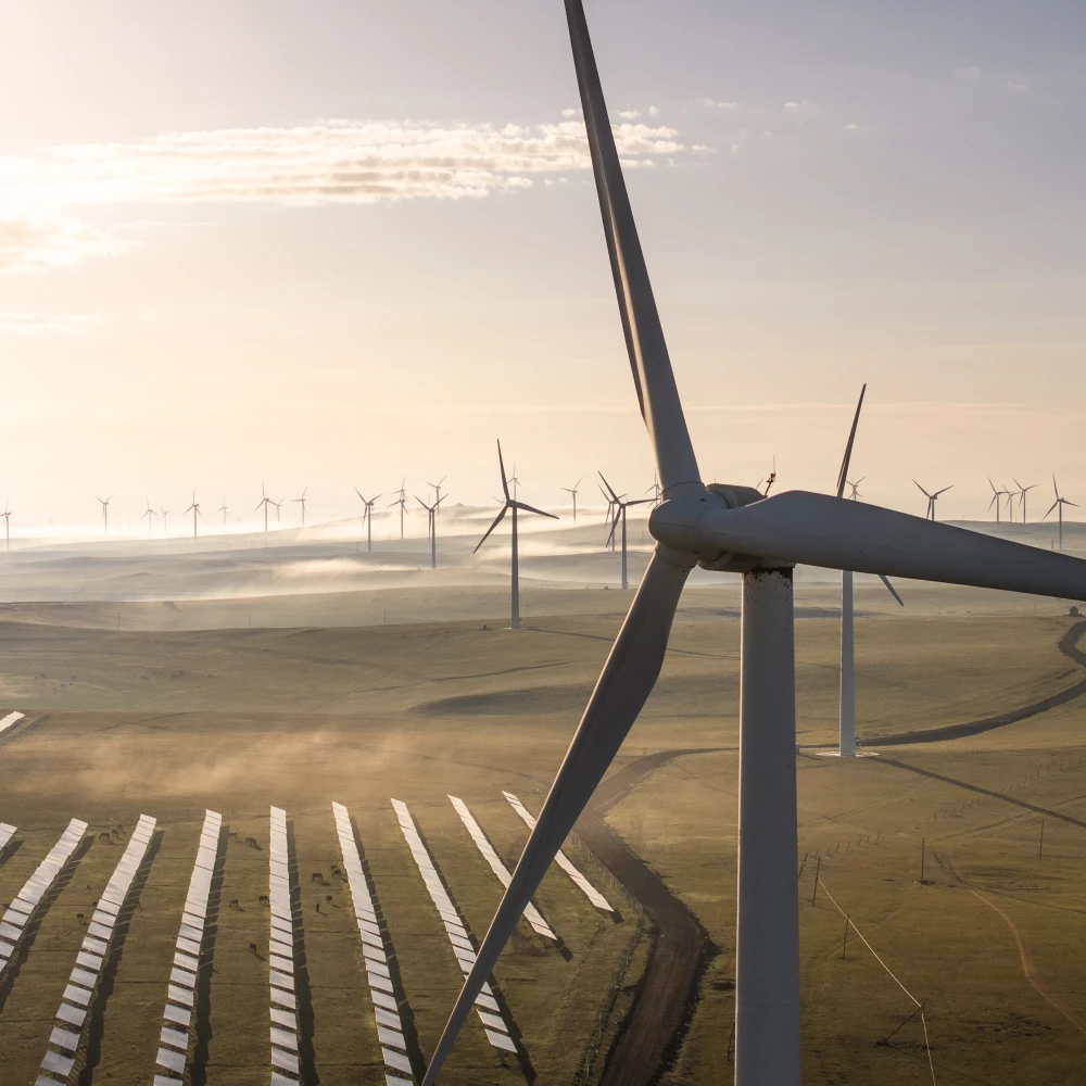 Aerial view of wind turbines and a solar farm operating together in a shared landscape