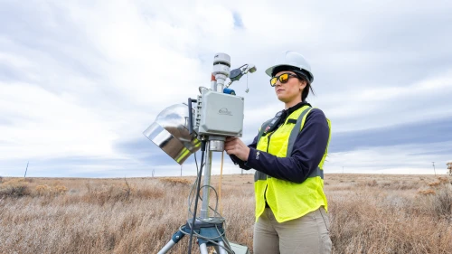 An Onterris employee setting up air sampling equipment in a field