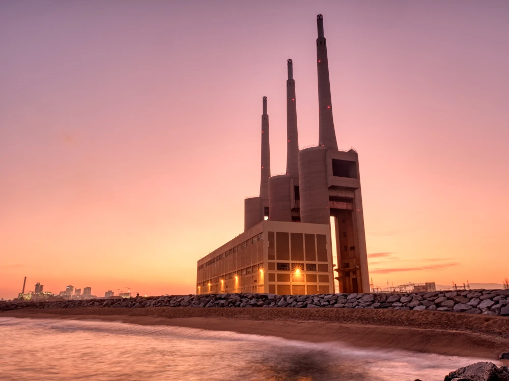 Thermal power plant with smokestacks at sunset near a waterfront
