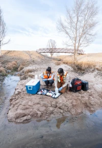 Employees collecting water samples in a stream.