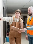 Two people wearing PPE Study a map in office