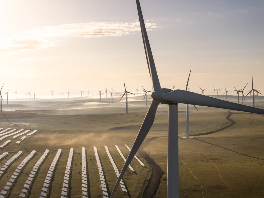 Aerial view of wind turbines and a solar farm operating together in a shared landscape