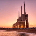 Thermal power plant with smokestacks at sunset near a waterfront