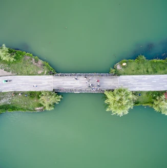 Top down aerial view of the pedestrian bridge in the middle of the pond in the park.
