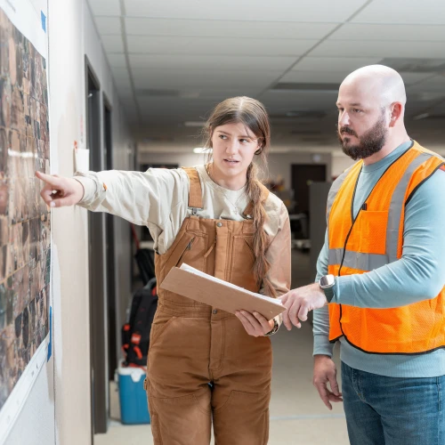 Two people wearing PPE Study a map in office