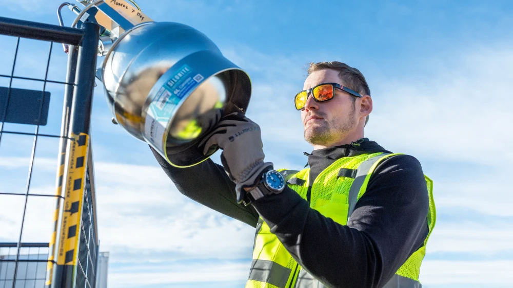 An employee in a safety vest inspecting industrial equipment outdoors.