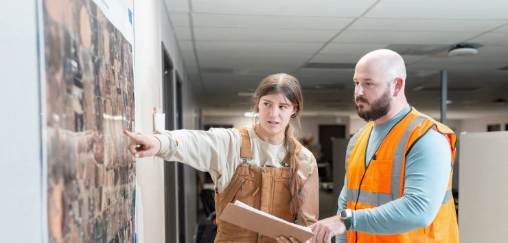 Two people wearing PPE Study a map in office