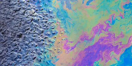 Colorful oil spill on water surface creating iridescent patterns and environmental pollution