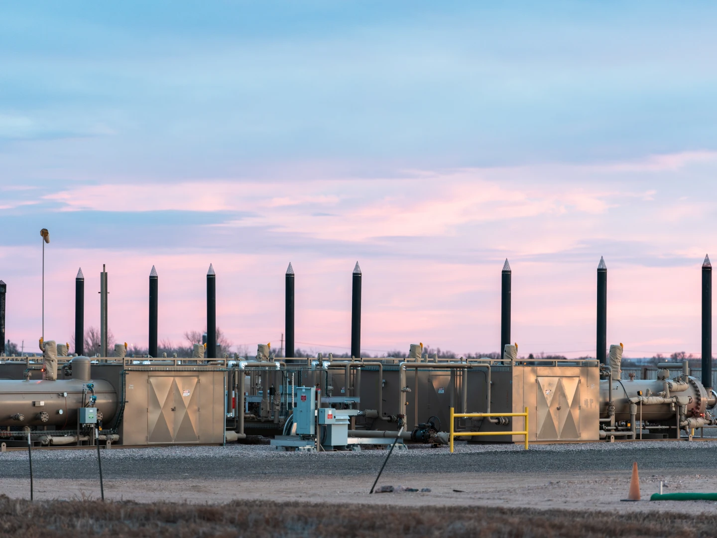 Natural gas processing facility with industrial equipment at sunset