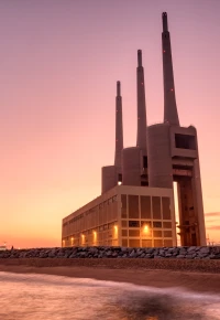 Thermal power plant with smokestacks at sunset near a waterfront
