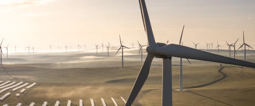 Aerial view of wind turbines and a solar farm operating together in a shared landscape