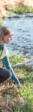 Environmental field scientist collecting a water sample from a stream.