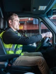 Employee in safety vest driving inside truck