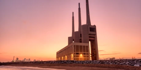 Thermal power plant with smokestacks at sunset near a waterfront