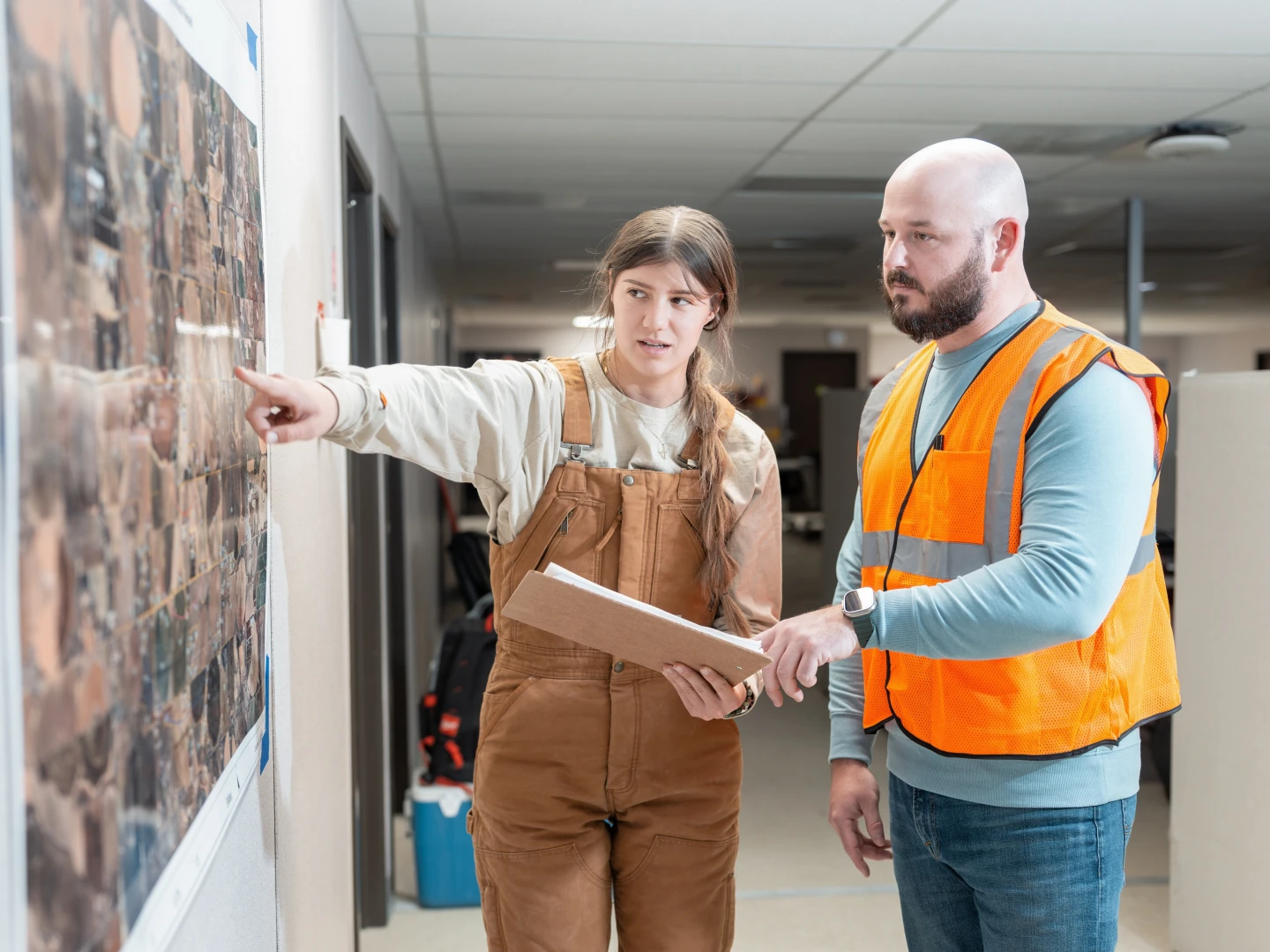 Two people wearing PPE Study a map in office